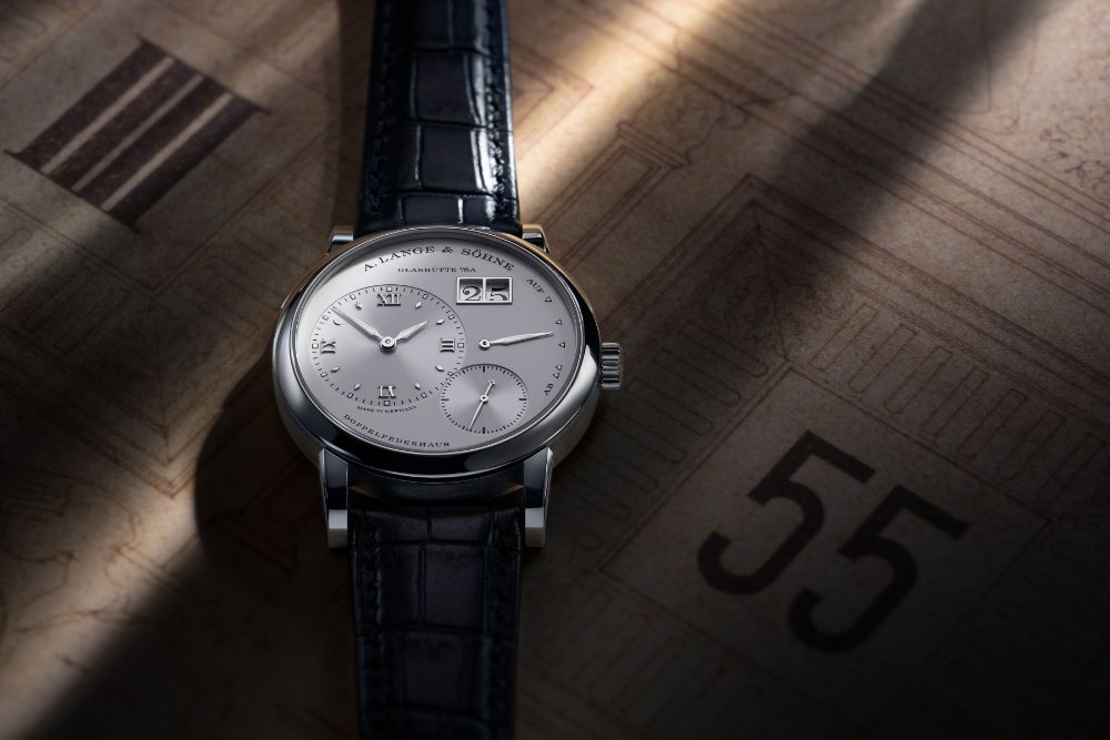 A Lange 1 wristwatch lying on the numeral drum of the Semper Opera clock, the outsize date at the top of its dial