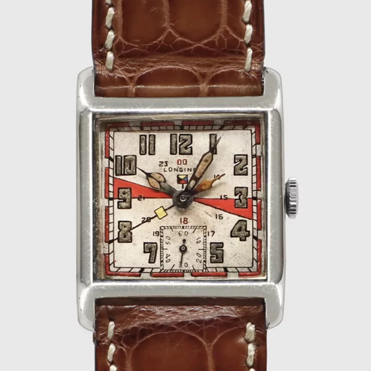 Longines dual-time wristwatch of 1925: square case, silvered dial with red sectors, Arabic numerals with an inner 13 to 24 track, a second orange-tipped hour hand and small seconds at six